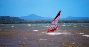 Windsurfer mit rotem Segel auf bewegtem Wasser 2026 — Sinnbild für Maciek Rutkowskis Foil-Rekord über die Ostsee von Schweden nach Polen