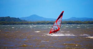 Windsurferin in Aktion mit rotem Segel und Gischt — Symbolbild fuer Maria Behrens, beste deutsche Wave-Windsurferin auf PWA-Rang 2 (2026)