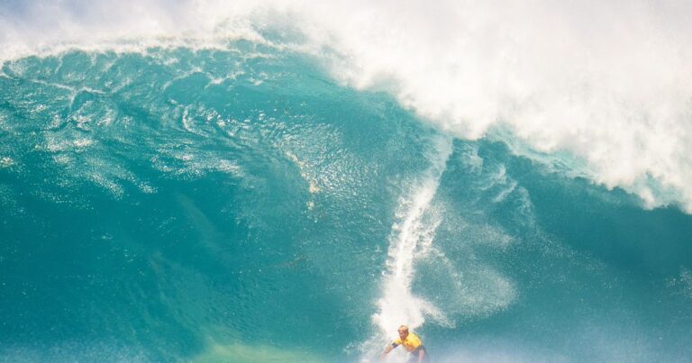 Big-Wave-Surfer im gelben Jersey droppt in eine massive Welle - Symbolbild zum Fiji Pro 2026 an Cloudbreak