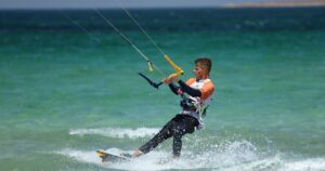 Junger Kitesurfer carvt auf Twintip-Board im Contest-Lycra — Symbolbild zur GKA Youth Twintip Kite-WM 2026 in St. Peter-Ording